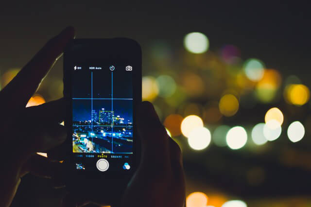 Someone taking a nighttime skyline photo on an iPhone